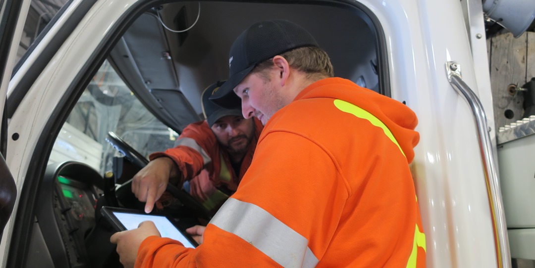 Ryan Marley (back) and Murray Hodgson (front) use a tablet with Workforce GIS to review upcoming work orders..