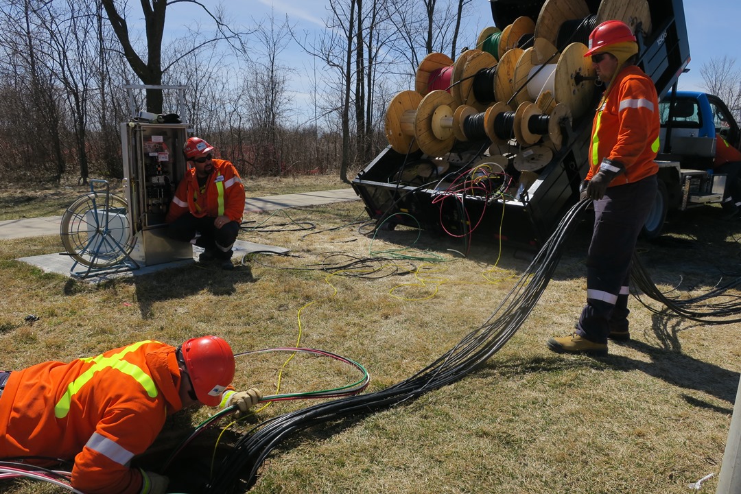 Streetlight Traffic Signal Technicians Curtis Smith (back), Murray Hodgson (right) and Nick Hodgson(front) install wiring through underground conduits for new traffic signals at Cataraqui Woods and Centennial.