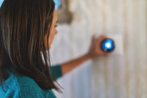 Stock photo of home owner adjusting smart thermostat