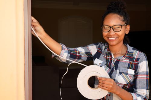 Stock photo of home owner applying weather stripping to door wat